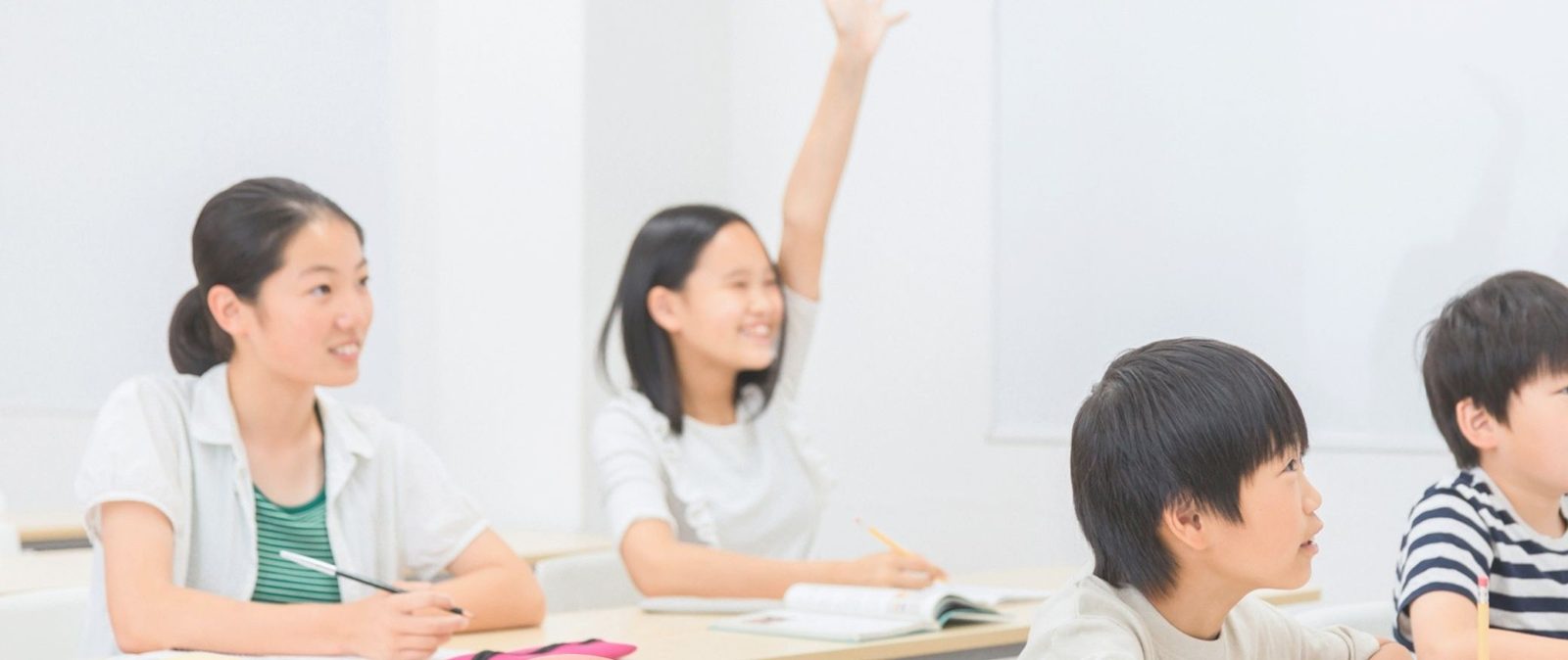 教室で笑顔で手を挙げる子どもたち